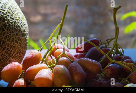 uva rosa e fichi sul tavolo, melone giallo su un bordo Foto Stock