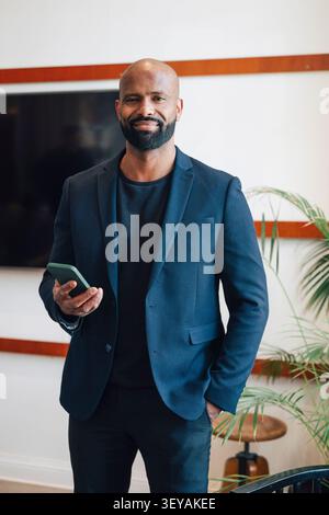 Ritratto di un uomo d'affari che tiene in mano il telefono mentre si trova in tasca sullo spazio di lavoro Foto Stock