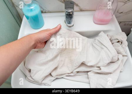 Problema di sudore giallo e macchie deodoranti sulla camicia bianca sotto le ascelle, sbiancando i vestiti a casa Foto Stock