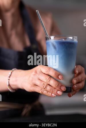Primo piano di Woman Bartender's Hand che serve Blue Matcha latte Foto Stock