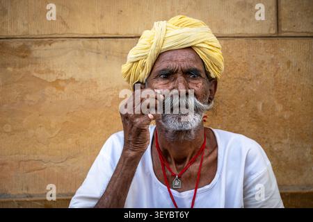 Ritratto di un uomo anziano che si torce i baffi a manubrio e indossa un turbante giallo a Jaisalmer, Rajasthan, India Foto Stock