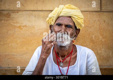 Ritratto di un uomo anziano che si torce i baffi a manubrio e indossa un turbante giallo a Jaisalmer, Rajasthan, India Foto Stock