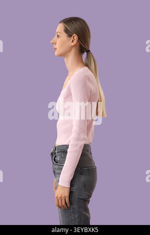 Profilo di una giovane donna in piedi su sfondo viola Foto Stock