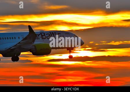 Belgrado, Serbia, 2 nov. 2025. Primo piano del profilo di un aereo passeggeri Air Baltic Airbus A220 che atterra contro un drammatico cielo del tramonto invernale Foto Stock