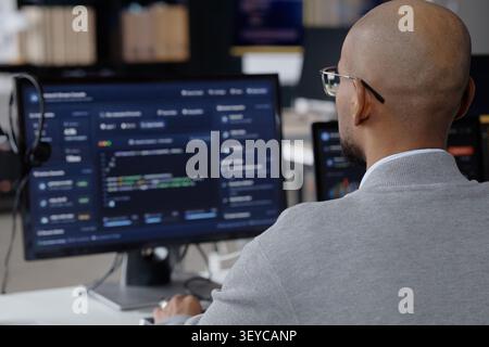 Uomo di mezza età che analizza i dati software in ufficio IT Foto Stock