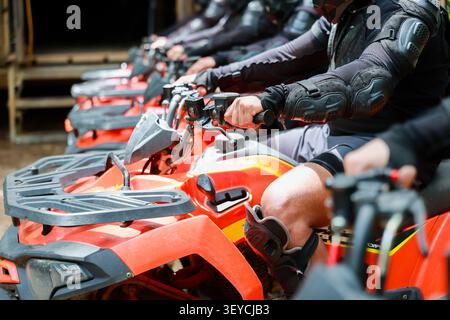 Un atv All Terrain Vehicle equipaggiamento protettivo casco sport outdoor Adventure di gruppo arancione atv che indossa abbigliamento protettivo e caschi sono rivestiti Foto Stock