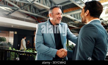 Uomo, agente immobiliare e stretta di mano in ufficio per il sorriso, la gestione della proprietà o l'affare di servizi. Cliente, agente immobiliare e stringere la mano all'agenzia per Foto Stock
