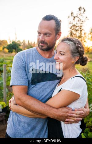 Coppia felice che abbraccia in un giardino al tramonto Foto Stock
