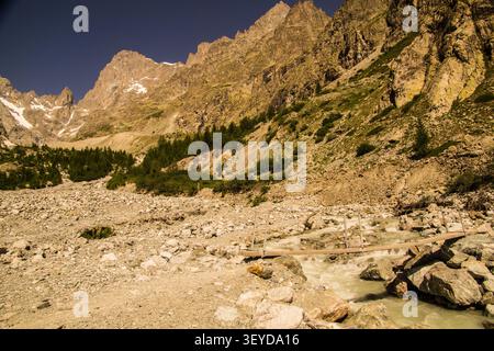 Il torrente di montagna scorre attraverso il paesaggio roccioso con un piccolo ponte e. Foto Stock