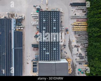 Vista aerea di una fabbrica di lastre di pietra con pannelli solari sul tetto e pile organizzate di materiali da costruzione nel cantiere, riga, Lettonia. Foto Stock