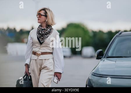 Donna d'affari che arriva in auto con bagagli e telefono, lavoro a distanza e stile di vita da viaggio Foto Stock