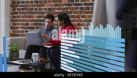 Due colleghi seduti, grafici di dati animati appaiono, donna indica l'uomo che analizza i dati su un laptop Foto Stock