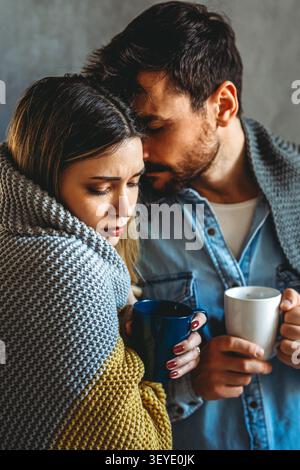 Uomo e donna malati avvolti in coperte che soffrono di raffreddore o influenza Foto Stock