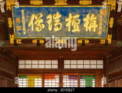 Trave dorata ornata di tempio con caratteri kanji dipinti e pannelli di cornice tradizionali blu, Kyoto, Giappone Foto Stock