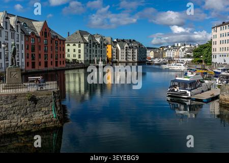Edifici colorati in stile Art Nouveau e barche ormeggiate si riflettono nelle acque calme del canale di Brosundet nella città portuale di Ålesund, More og Romsdal, Norvegia Foto Stock