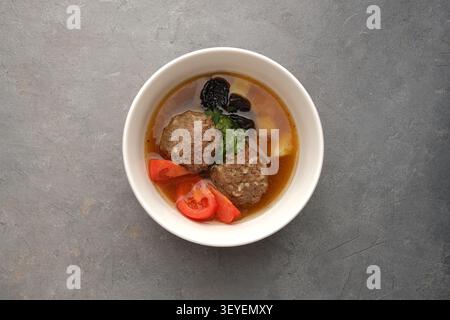 Zuppa di polpette fatta in casa con pomodori, erbe, prugne e patate in un recipiente bianco Foto Stock