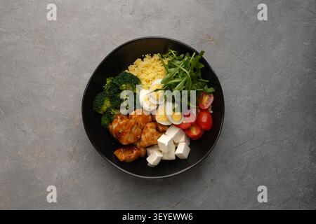 Sana ciotola con pollo glassato, broccoli, uova, pomodori, verdure e feta Foto Stock