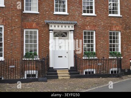 Topsham England: Edificio in mattoni rossi caratterizzato da una porta bianca fiancheggiata da colonne rotonde e finestre multiple con cornici bianche Foto Stock