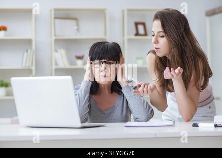 Figlia di spiegare alla mamma come usare il computer Foto Stock
