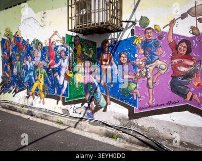 Colorato murale di Street art su un muro di un edificio che presenta gente che cucina e celebra la cultura locale, firmato da kionfurniture.Official Foto Stock