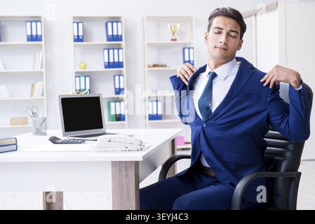 Giovane imprenditore facendo sport stretching al lavoro Foto Stock