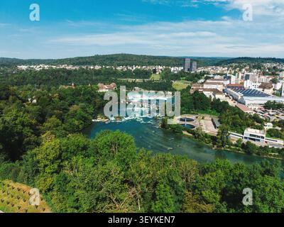 Vista aerea delle Cascate del Reno con lussureggianti foreste verdi, il fiume che scorre attraverso edifici urbani e un cielo azzurro limpido a Neuhausen am Rheinfall, Schaff Foto Stock