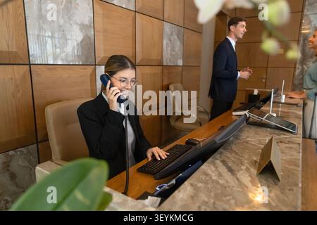 L'addetto alla reception comunica con gli ospiti telefonando alla reception dell'hotel Foto Stock
