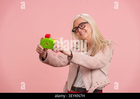 Anziana che gode di un invecchiamento attivo con una macchina fotografica giocattolo Foto Stock