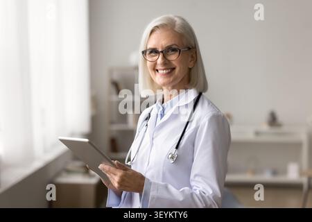 Medico femminile sorridente che guarda la fotocamera che tiene il pc pad Foto Stock