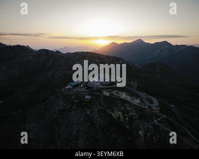 Veduta aerea della strada alpina Grossglockner che si snoda attraverso aspre montagne al tramonto, con un parcheggio sul crinale nel quartiere Zell am SEE Foto Stock