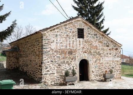 Chiesa ortodossa storica in pietra con muratura tradizionale, porta in legno ad arco, tetto a tegole e motivi decorativi a croce nelle pareti. Foto Stock