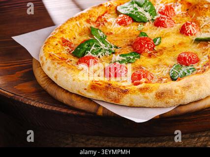 Pizza margherita appena sfornata con formaggio fuso, salsa di pomodoro, basilico e pomodori ciliegini Foto Stock