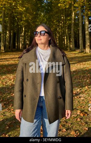 Donna in piedi nel vicolo degli alberi autunnali nel parco di Versailles. Foto Stock