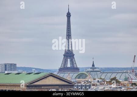 Torre Eiffel che si erge sopra lo skyline di Parigi con tetti classici e cielo nuvoloso, iconico simbolo della Francia. Foto Stock