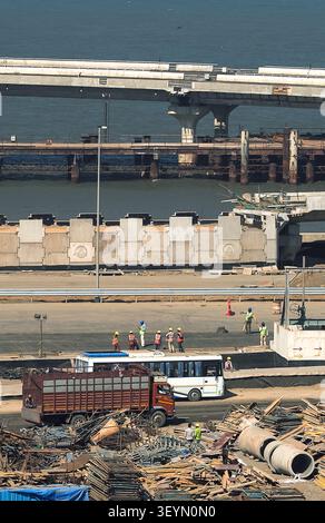 Una vista rialzata che mostra i lavori di costruzione in corso su una nuova strada costiera o progetto di ponti a Mumbai, con macchinari e materiali pesanti visibili Foto Stock