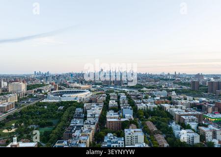 Ampia vista aerea sullo skyline di New York con fitti edifici residenziali, stadio, corridoi fluviali, torri lontane e luci soffuse di sera Foto Stock