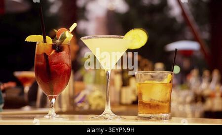 Una varieta' di cocktail colorati esposti elegantemente su un bancone bar con uno sfondo scuro Foto Stock