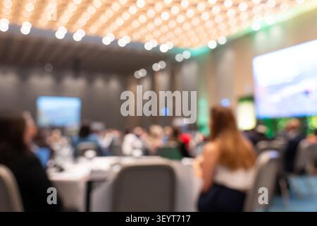 Un'immagine bokeh esteticamente piacevole e completamente sfocata dei partecipanti che guardano una presentazione in una grande sala convegni e conferenze con l Foto Stock