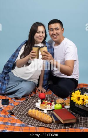 Una giovane coppia romantica che si guarda mentre brinda al picnic Foto Stock