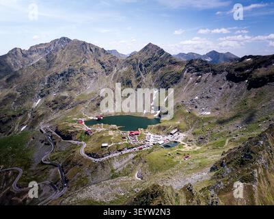 Veduta aerea della tortuosa strada Transfagarasan che passa dal lago Balea, circondata dalle aspre vette dei Monti Fagaras, Comuna Arefu, Judetul A. Foto Stock