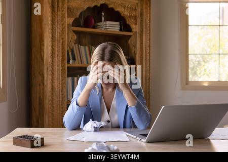 Una donna d'affari stressata, seduta con documenti sgualciti Foto Stock