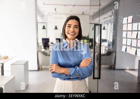 Donna professionale sicura di sé in un ufficio moderno vicino a una lavagna di vetro Foto Stock