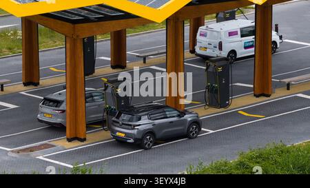 Muiden, Paesi Bassi - 11 giugno 2026: Veduta aerea della stazione di ricarica Fastned con veicoli elettrici parcheggiati e in carica sotto una tettoia solare a Noord-H. Foto Stock
