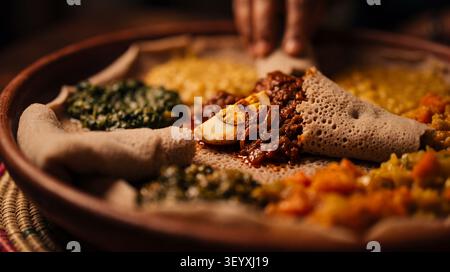 Autentico injera etiope servito con Doro Wat, uno stufato di pollo speziato con miscela di spezie berbere, cipolle, aglio e uova sode. Il grande fermento Foto Stock