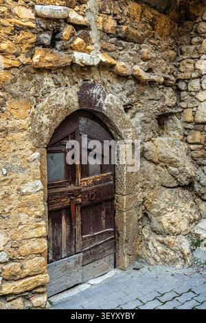 Antica porta ad arco in legno inserita in un muro di pietra grezza di un villaggio medievale. Tussio, Prata d'Ansidonia, Provincia dell'Aquila, Abruzzo, Italia, Europa Foto Stock