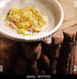 Un piatto creativo con ingredienti freschi, placcato elegantemente in una semplice ciotola. La superficie rustica in legno aggiunge calore, evidenziando la vivace presentazione del cibo. Foto Stock