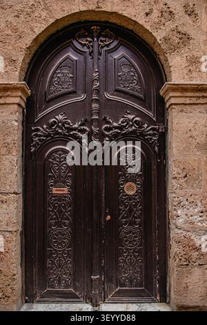Intricata porta di legno con intagli ornati in un edificio storico da una strada pittoresca Foto Stock
