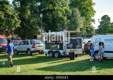 Giornata soleggiata nel parco di Saffron Walden con un food truck e persone che godono del loro cibo da asporto Foto Stock