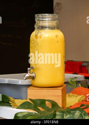 Distributore di succo di frutta giallo in un barattolo di vetro con rubinetto durante un evento organizzato Foto Stock