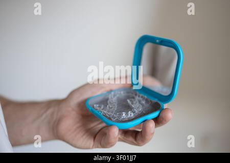 custodia blu neutra con allineatori trasparenti in una prospettiva portatile ravvicinata su uno sfondo neutro interno per l'ortodonzia dentale, caso di utilizzo e. Foto Stock